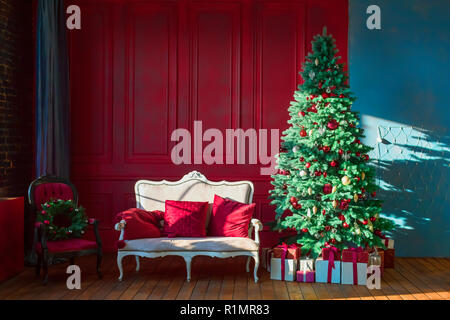 Christmas tree in royal interior. New Year's Living Room with antique stylish white sofa with luxurious golden accessories. Gifts, Christmas decoratio Stock Photo