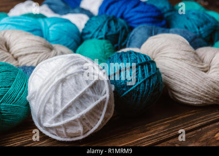 close up view of white, blue and green yarn for knitting on wooden surface Stock Photo