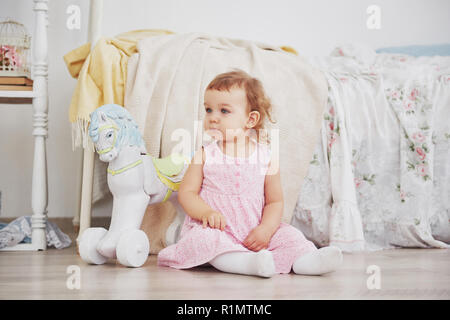 Beautiful little girl playing toys. Blue-eyed blonde. White chair. Children's room. Happy small girl portrait. Childhood concept Stock Photo