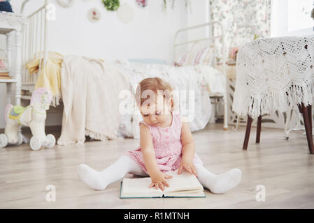 Beautiful little girl playing toys. Blue-eyed blonde. White chair. Children's room. Happy small girl portrait. Childhood concept Stock Photo