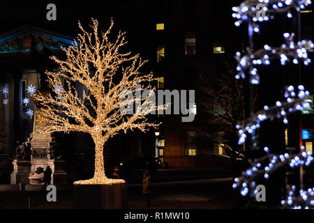 Tree decorated (covered) with christmas lights illuminated at on winter nigh at Place d'Armes in Montreal Quebec, Canada. Stock Photo