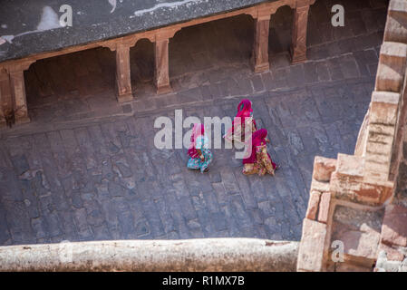 Three women in colourful traditional Rajasthani dresses walking across a courtyard in Jodhpur palace,  India. Stock Photo