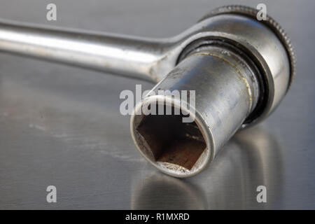 Old socket wrenches with a handle. Accessories for a workshop mechanic on a tin table. Light background. Stock Photo