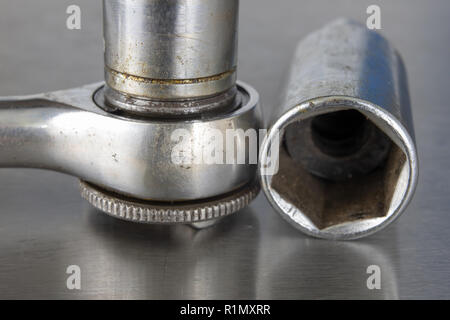 Old socket wrenches with a handle. Accessories for a workshop mechanic on a tin table. Light background. Stock Photo