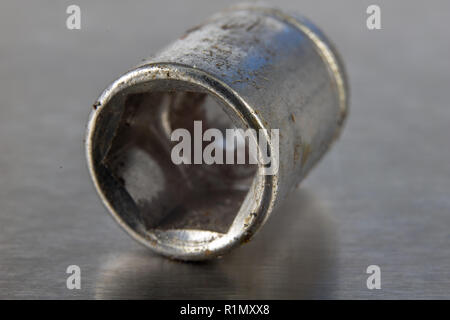 Old socket wrenches with a handle. Accessories for a workshop mechanic on a tin table. Light background. Stock Photo