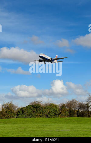 LONDON, ENGLAND - NOVEMBER 2018: Wide angle view of a British Airways Airbus A320 short haul jet passing over fields on its final approach to land at  Stock Photo