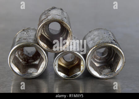 Old socket wrenches with a handle. Accessories for a workshop mechanic on a tin table. Light background. Stock Photo