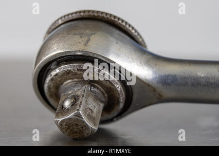 Old socket wrenches with a handle. Accessories for a workshop mechanic on a tin table. Light background. Stock Photo