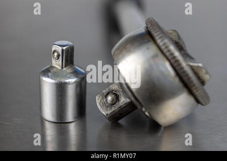 Old socket wrenches with a handle. Accessories for a workshop mechanic on a tin table. Light background. Stock Photo