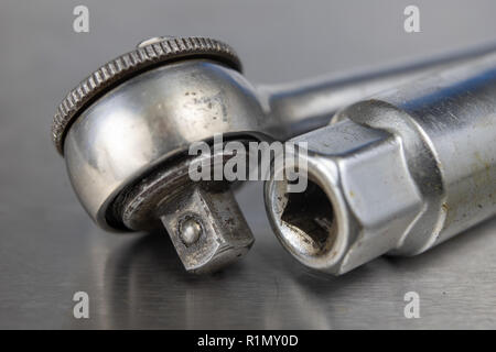Old socket wrenches with a handle. Accessories for a workshop mechanic on a tin table. Light background. Stock Photo