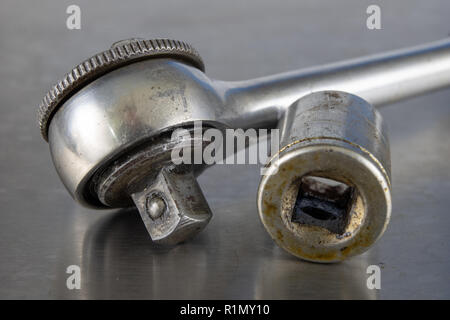 Old socket wrenches with a handle. Accessories for a workshop mechanic on a tin table. Light background. Stock Photo