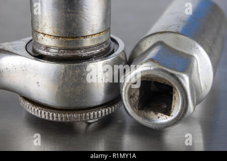 Old socket wrenches with a handle. Accessories for a workshop mechanic on a tin table. Light background. Stock Photo