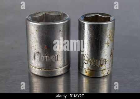 Old socket wrenches with a handle. Accessories for a workshop mechanic on a tin table. Light background. Stock Photo