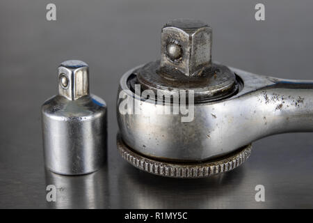 Old socket wrenches with a handle. Accessories for a workshop mechanic on a tin table. Light background. Stock Photo