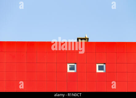 Modern Facade with Red Tiles and Two Small Windows. Seagull, Chimney. Copy Space. Stock Photo