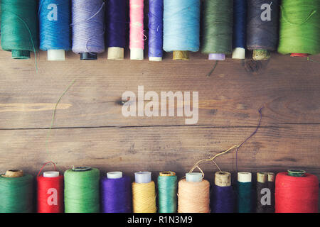 Bobbins with colorful threads on old wooden table background Stock Photo