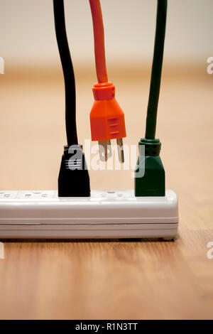 Electrical cords and a power strip surge protector outlet with one cord unplugged Stock Photo