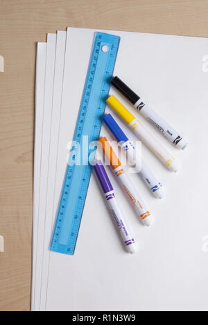 School and art supplies including color markers, a blue ruler, and white tag board on a desktop Stock Photo