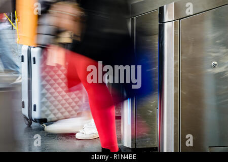 Side view of women with rolling suitcases passing through stainless steel ticket gates in a public transportation station in Paris with motion blur. Stock Photo