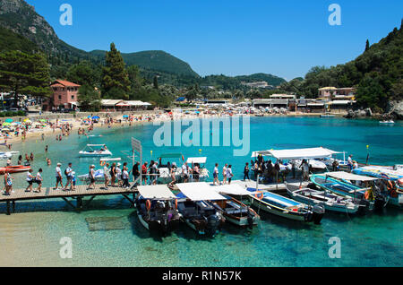 Corfù, Greece, July 20, 2018: Tourists on the pier waiting to be boarded on boats, on the bottom the green and turquoise sea, people under the umbrell Stock Photo