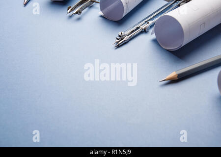 Tools for drawing and rolls of blueprints on a blue background Stock Photo