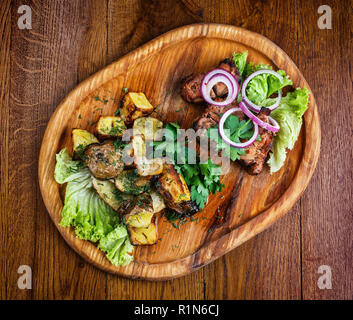Board with barbecue and baked potatoes. Snacks for beer in the pub. Stock Photo