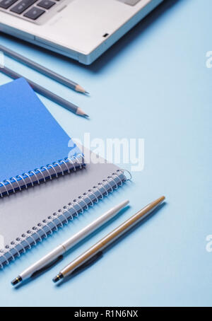 Pencils next to notebooks and pens on a blue background Stock Photo