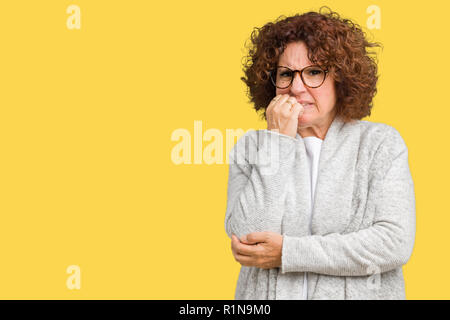 Beautiful middle ager senior woman wearing jacket and glasses over isolated background looking stressed and nervous with hands on mouth biting nails.  Stock Photo