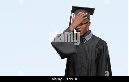 Young graduated african american man over isolated background surprised with hand on head for mistake, remember error. Forgot, bad memory concept. Stock Photo