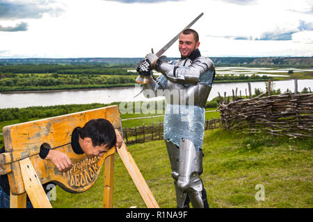 Dramatization penalty in the middle ages. Knight swung his sword at the prisoner. Knightly armor and weapon. Semi - antique photo. Stock Photo