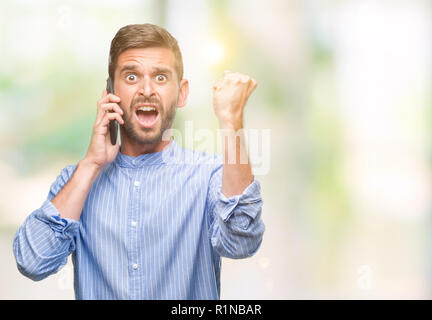 Young handsome man speaking on the phone over isolated background annoyed and frustrated shouting with anger, crazy and yelling with raised hand, ange Stock Photo