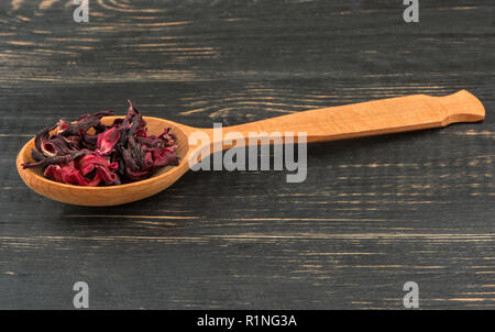 Dry karkade tea in a spoon on wooden background closeup Stock Photo