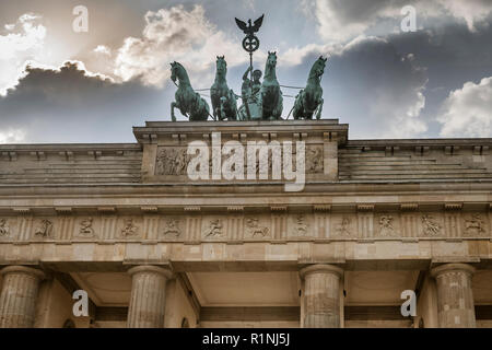 The historic Quadriga on top of the Brandenburg Gate in Berlin sits against a dramatic stormy sky at dusk. Stock Photo