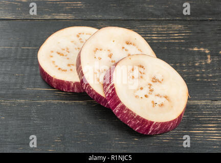 Three slices of fresh eggplant on wooden background Stock Photo