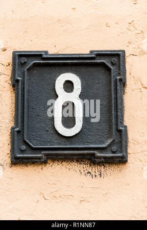 metallic house number, black on the wall Stock Photo