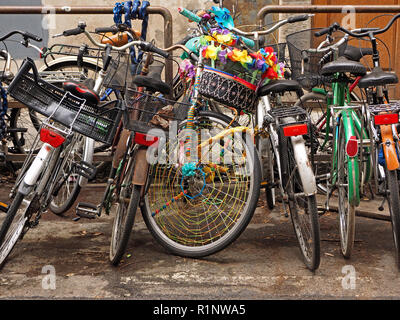 brightly decorated colourful push bike amongst muddle of parked pedal cycles parked at cycle rack in typical town street in Florence, Tuscany, Italy Stock Photo