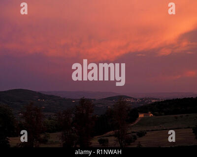 Fiery evening sky with orange and purple clouds looking down towards Fiesole, over the Medici Pratolino Estate above Florence, Tuscany, Italy Stock Photo