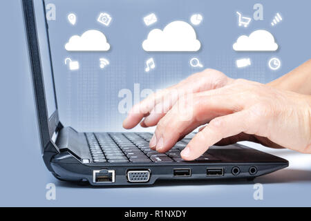 Cloud computing concept showing hands typing on computer keyboard with common Internet media icons around clouds from digital data. Stock Photo
