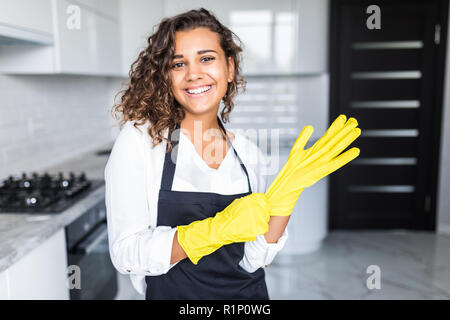 Portrait of young attractive caucasian brunette housewife at kitchen wearing the yellow rubber gloves. Stock Photo