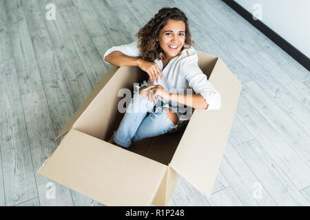 woman having fun and riding in cardboard boxes at new home Stock Photo