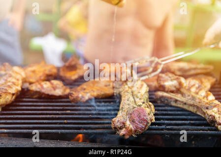 Friends frying the meat ribs and steaks, barbecue on open air, picnic, rest on weekends Stock Photo