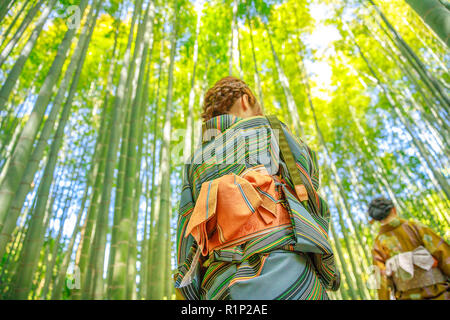 Hanami in spring season with unidentifiable women with green Japanese kimono in bamboo grove of Take-dera Hokoku-ji Temple at sunset in Kamakura, Japan city. Japanese culture and lifestyle. Stock Photo