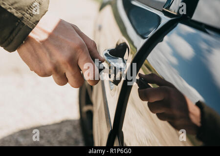 Close-up of a man's hand opens the car door with a key. Stock Photo