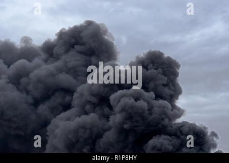 Forms and shapes in a cloud of toxic pollution smoke from a factory fire against a cloudy blue sky. Stock Photo