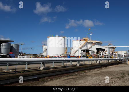 Gas and fuel storage tanks at an oil refinery on a clear day with blue skies and puffy clouds. Stock Photo