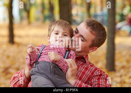 Father and son are playing and having fun in autumn city park. They posing, smiling, playing. Bright yellow trees. Stock Photo