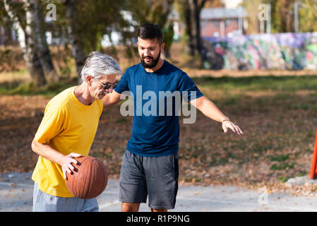 Father and son playing basketball in the park Stock Photo