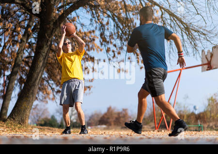 Senior father and son playing basketball in the park Stock Photo