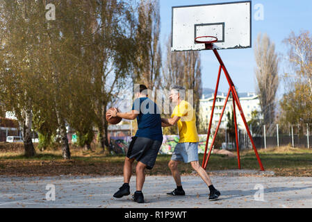 Senior father and son playing basketball in the park Stock Photo