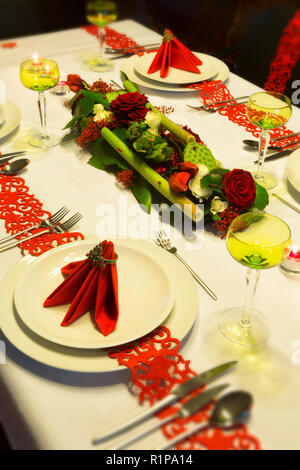 Table setting red napkins and glasses, gold plates. Interior of a